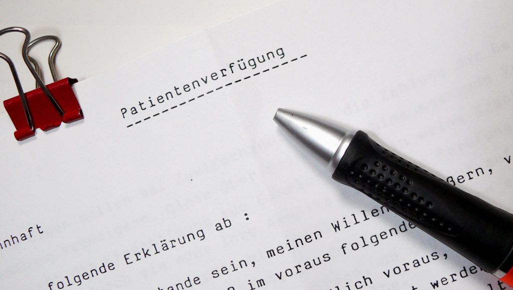 Dokument zur Patientenverfügung mit Kugelschreiber und roter Büroklammer.